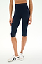 A person wearing SPLITS59 Airweight High Waist 16" Capri Legging in Indigo and white sneakers, shown from shoulders to feet, standing against a plain white background.