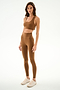 Woman wearing the SPLITS59 Sara Airweight Bra - Toffee with matching high-waisted leggings and beige sneakers, standing against a white background.