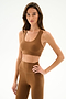 A woman models the SPLITS59 Sara Airweight Bra - Toffee with matching high-waisted leggings, posing against a plain white background.