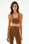 A woman faces forward wearing the SPLITS59 Sara Airweight Bra - Toffee and matching leggings, long hair down, neutral expression. Plain white background. HTS 6109.90.1090.
