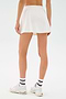 A person wearing the SPLITS59 Venus High Waist Rigor Skort with white sneakers and white socks featuring black stripes, standing against a plain light background.