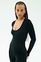 A woman with long braided hair wears the SPLITS59 Chloe Airweight Jumpsuit in black and gold hoop earrings, standing against a plain light background.
