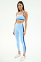 A woman wears the SPLITS59 Sam High Waist Rigor 7/8 leggings in Skylight/Cobalt, featuring dark blue side stripes, paired with a matching sports bra and white sneakers.