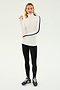 A person wearing a SPLITS59 Jackson Rib Full Length Turtleneck in White/Indigo, black leggings, and black athletic shoes stands against a plain background.