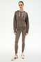 A woman stands against a plain background, wearing the SPLITS59 Joey Fleece Hoodie in Lentil and matching leggings, both crafted from a soft modal spandex blend, paired with beige sneakers featuring maroon stripes.