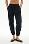 Model wears the SPLITS59 Megan Woven Nylon Jogger in black, featuring a cinched waistband and hands in pockets, paired with black ballet flats. Shown from chest down against a plain background.