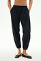 Model wears the SPLITS59 Megan Woven Nylon Jogger in black, featuring a cinched waistband and hands in pockets, paired with black ballet flats. Shown from chest down against a plain background.