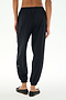 A person is seen from behind, standing against a white background, wearing SPLITS59 Megan Woven Nylon Jogger in black paired with black flat shoes.