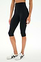 A person wearing SPLITS59 Airweight High Waist 16" Capri Legging in black and white sneakers stands against a plain white background.