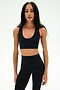 Wearing the SPLITS59 Sara Airweight Bra in black and matching leggings, a person with long braided hair stands against a plain white background—an ideal outfit for hot yoga or Pilates.