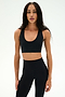 Wearing the SPLITS59 Sara Airweight Bra in black and matching leggings, a person with long braided hair stands against a plain white background—an ideal outfit for hot yoga or Pilates.