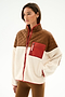 Woman in the SPLITS59 Skylar Sherpa Jacket - Creme/Toffee with brown quilted shoulders, red chest pocket, and cream fleece body, styled with brown pants.