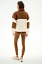 Woman facing away, wearing the SPLITS59 Skylar Sherpa Jacket - Creme/Toffee with brown leggings and beige sneakers, standing against a plain white background.