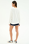 A person stands on a white background, facing away, wearing the SPLITS59 Andie Oversized Fleece Varsity Graphic Sweatshirt in white. This casually refined look is made in Los Angeles.