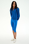 A person with long hair down stands on a white background, arms behind their back, wearing the SPLITS59 Bonnie Knit Half Zip in Classic Blue/White—a quarter-zip sweatshirt crafted from a soft rayon blend—paired with blue knee-length leggings made from comfortable nylon fabric and white sneakers.