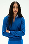 A person with long curly hair stands with arms crossed against a plain white background, wearing the SPLITS59 Bonnie Knit Half Zip in Classic Blue/White—a bright blue sweater crafted from a soft rayon and nylon blend, detailed with white stripes on the collar and cuffs.