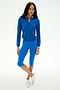 A woman stands against a white background, wearing the SPLITS59 Bonnie Knit Half Zip in Classic Blue/White, paired with matching blue knee-length nylon leggings and white sneakers.