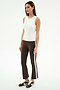 A woman stands against a plain white background wearing the SPLITS59 Raquel High Waist Supplex Crop in Dark Chocolate/White and a white sleeveless top, paired with brown Nike sneakers.