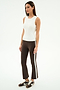 A woman stands against a plain white background wearing the SPLITS59 Raquel High Waist Supplex Crop in Dark Chocolate/White and a white sleeveless top, paired with brown Nike sneakers.