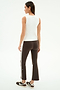 A woman stands facing away, wearing the SPLITS59 Raquel High Waist Supplex Crop in Dark Chocolate/White, a sleeveless white nylon top, and black sneakers against a white background.