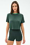 A woman in the SPLITS59 Djuna Crop Ringer - Military/Spearmint stands against a white background, wearing the dark green short-sleeve cropped T-shirt and matching high-waisted shorts made from soft viscose and elastane.