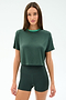 A woman in the SPLITS59 Djuna Crop Ringer - Military/Spearmint stands against a white background, wearing the dark green short-sleeve cropped T-shirt and matching high-waisted shorts made from soft viscose and elastane.
