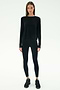 A person stands facing forward in SPLITS59's Djuna Long Sleeve - Black, paired with black leggings and sneakers—ideal activewear for cool weather workouts—against a plain white background.