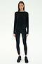 A person stands facing forward in SPLITS59's Djuna Long Sleeve - Black, paired with black leggings and sneakers—ideal activewear for cool weather workouts—against a plain white background.