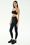 A woman stands against a white background wearing SPLITS59’s Airweight Super High Waist 7/8 leggings in black and a sports bra—breathable and ideal for hot yoga sessions.