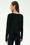 A woman faces away, wearing the SPLITS59 Djuna Long Sleeve in black against a plain light background.