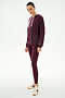 A person wears the SPLITS59 Joey Fleece Hoodie in Dark Cherry, crafted from a soft modal and spandex blend, paired with matching leggings and white sneakers, standing against a plain white background.