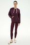 A woman stands against a plain white background wearing the SPLITS59 Joey Fleece Hoodie in Dark Cherry, featuring white drawstrings, paired with matching burgundy leggings crafted from a soft modal and spandex blend, and beige sneakers.