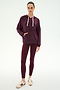A woman stands against a plain white background wearing the SPLITS59 Joey Fleece Hoodie in Dark Cherry, featuring white drawstrings, paired with matching burgundy leggings crafted from a soft modal and spandex blend, and beige sneakers.