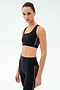 A person models the SPLITS59 Lexi Rigor Bra in Black/Dark Chocolate, paired with high-waisted leggings featuring white side stripes, against a plain background—perfect for high-impact workouts.