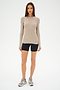 A person in a beige long-sleeve top, SPLITS59 Airweight High Waist Short in black, and gray sneakers stands against a white background.