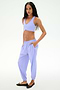 A person stands against a white background wearing the SPLITS59 Megan Woven Nylon Jogger in Purple Haze with black flats, hands in pockets, looking at the camera.
