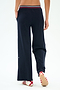 A person is shown from the back wearing SPLITS59 Michele Airweight Trouser in Indigo with hands in pockets and white slip-on shoes featuring red and navy stripes, standing on a white background.