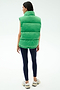 A woman faces away, wearing the SPLITS59 Summit Nylon Puffer Vest in Grass—a sleeveless, lightweight insulated vest—paired with dark leggings and sneakers, set against a plain light background.