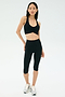 A woman stands against a plain background wearing a black sports bra, SPLITS59 Airweight High Waist 16" Legging in black, and white athletic shoes.