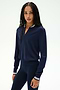 A woman with long braided hair wears the SPLITS59 Bonnie Knit Half Zip in Indigo/White, paired with matching navy leggings, both crafted from a soft rayon-nylon blend, as she stands against a plain light background.