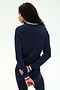 A woman with long dark hair stands with her back to the camera, wearing the SPLITS59 Bonnie Knit Half Zip in Indigo/White—a navy long-sleeve top with white trim—paired with matching navy pants, all crafted from a soft rayon blend.