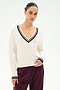 A woman is wearing the SPLITS59 Jemma Knit V Neck in White/Black—a soft, comfortable sweater crafted from a rayon and nylon blend—paired with maroon pants and standing against a plain light background.