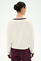 A person stands with their back to the camera, wearing the SPLITS59 Jemma Knit V Neck in white with black trim, crafted from a soft rayon blend, paired with burgundy pants against a plain light background.