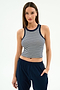A woman stands against a white background, wearing the SPLITS59 Kiki Rib Crop Tank in White/Indigo Stripe and navy pants, with one hand in her pocket.