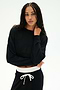 A woman wears the SPLITS59 Noah Fleece Crop Sweatshirt in black with matching drawstring pants, posing against a white background with one hand on her neck. This dance-inspired look is made in Los Angeles.