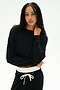 A woman wears the SPLITS59 Noah Fleece Crop Sweatshirt in black with matching drawstring pants, posing against a white background with one hand on her neck. This dance-inspired look is made in Los Angeles.