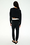 A person with long hair faces away, wearing the SPLITS59 Noah Fleece Crop Sweatshirt in black, paired with black pants and flats, set against a plain white background.