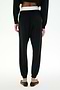 Model wears SPLITS59 Andie Dual Waist Sweatpant - Black/White, featuring a soft modal blend with a contrasting white waistband, paired with black flat shoes, shown from the back against a plain white background.