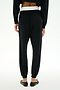 Model wears SPLITS59 Andie Dual Waist Sweatpant - Black/White, featuring a soft modal blend with a contrasting white waistband, paired with black flat shoes, shown from the back against a plain white background.
