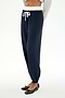A person is wearing the SPLITS59 Andie Dual Waist Sweatpant in Indigo/White, featuring a comfortable baggy sweatpant fit and a white drawstring. The joggers are styled with a gray sweater and black ballet flats, against a white background. Made in Los Angeles.